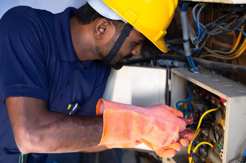 Electrical engineer with protective workwear repairing or connecting wires by using screw driver.